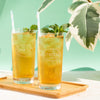 Two filled glasses of iced tea garnished with mint.