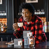 Scottie Pippen holding a tea cup looking at the camera smiling.