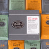 Grey box with embossed Smith logo shield and white label on top of green, black and orange sachets around the box.