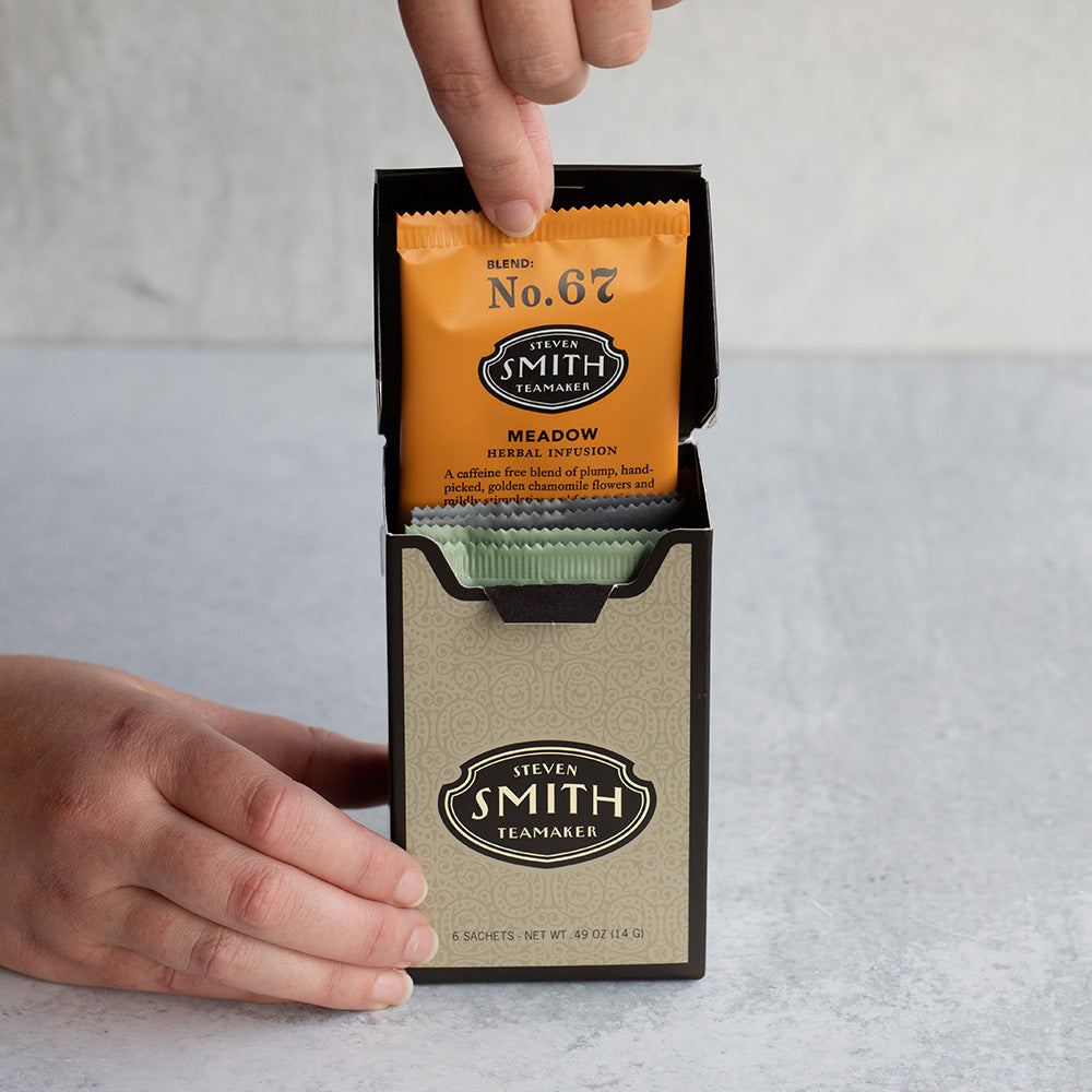 Hand pulling orange tea sachet out of box.